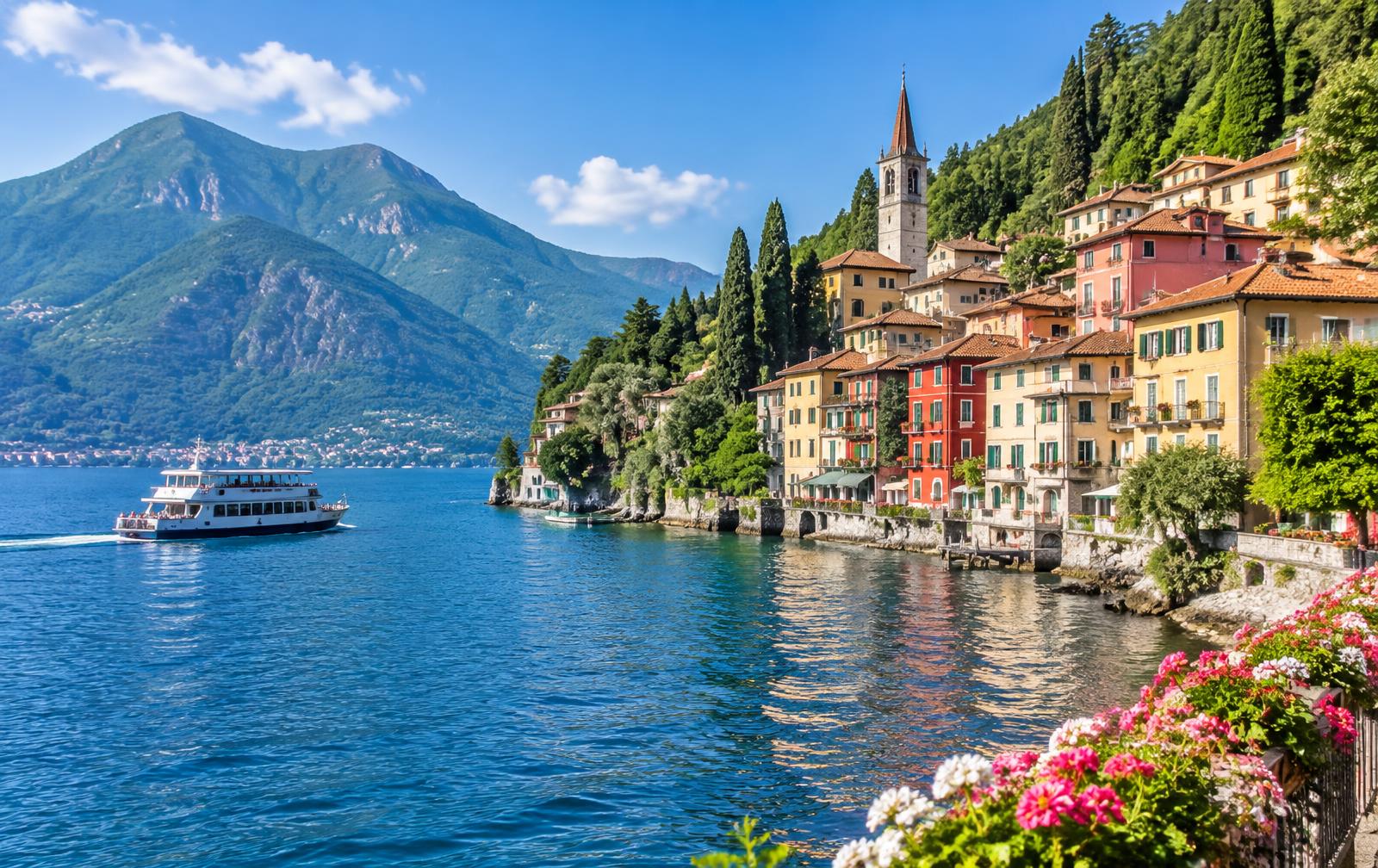 Pastel houses of Varenna on Lake Como with a passenger ferry and green mountains